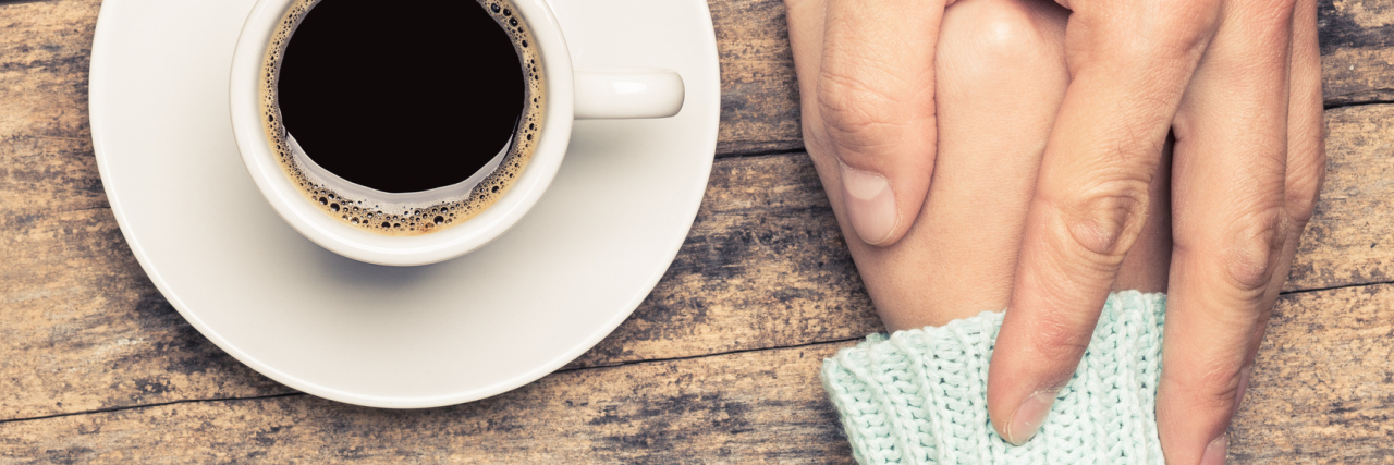 close up of people holding hands on table beside cup of coffee
