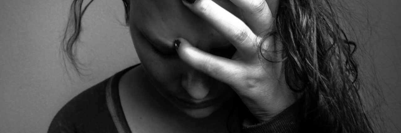 7 Things You Should Expect When I’m Having an Anxious Episode black and white portrait of emotional woman holding head looking down with messy hair at home, stress, depressed, sad, somber