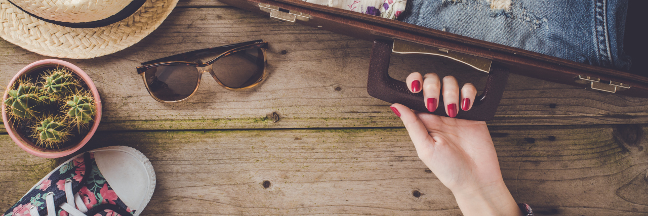 7 Tips for Traveling With a Chronic Illness Travel preparations on wooden table