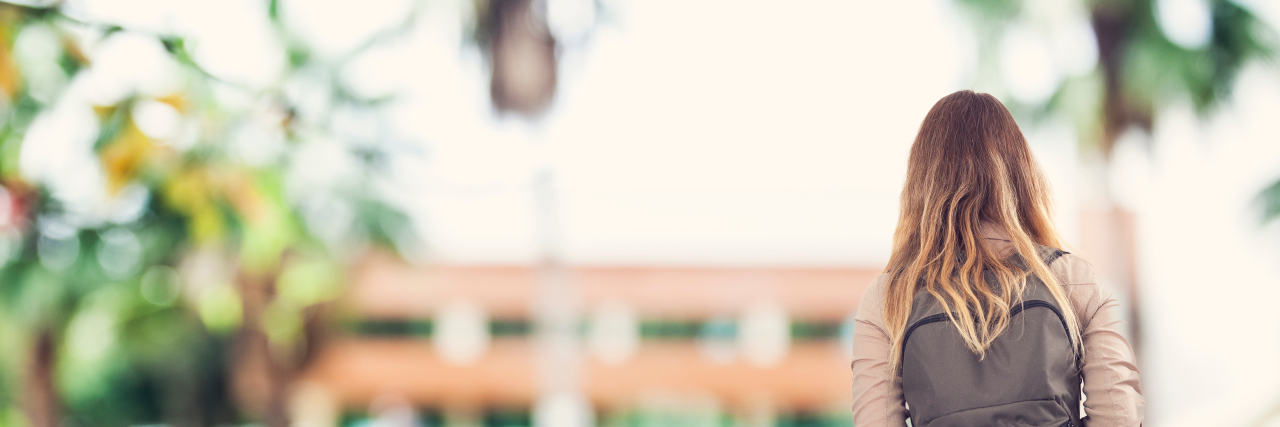 Having to Put Life on Hold to Find a Diagnosis the back of a girl with a book bag standing in front of school