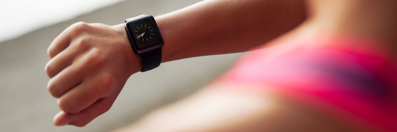 How a Smart Watch Negatively Affected My Obsessive Compulsive Disorder Close up image of young woman checking the time on smartwatch device after jog, outdoors.