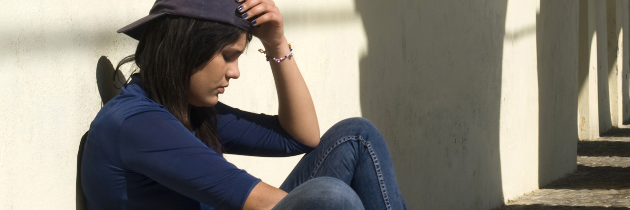 Childhood Emotional Abuse Made Me Afraid I Look Like My Mother woman sitting against wall sad depression