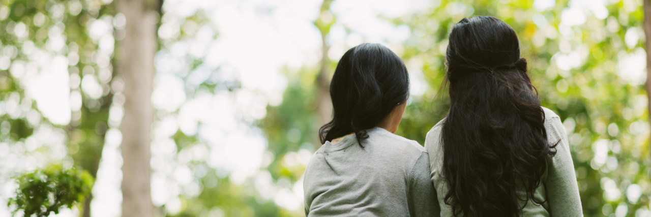 Why It's Hard to Share Your Story With Illness Rear view of two female friends resting in park