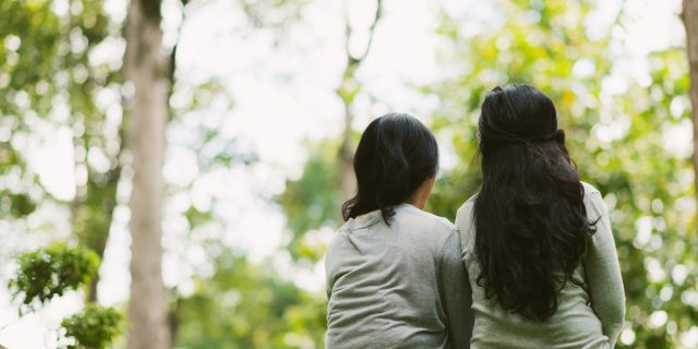 Why It's Hard to Share Your Story With Illness Rear view of two female friends resting in park
