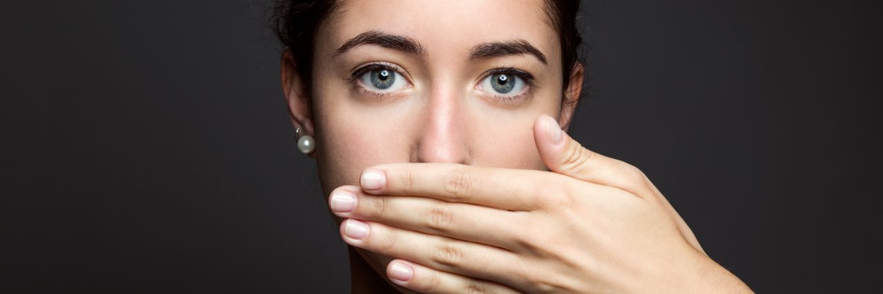 To Family Members Who Tell Me to Stay Silent About Advocacy young woman covering her mouth with hand. Isolated.