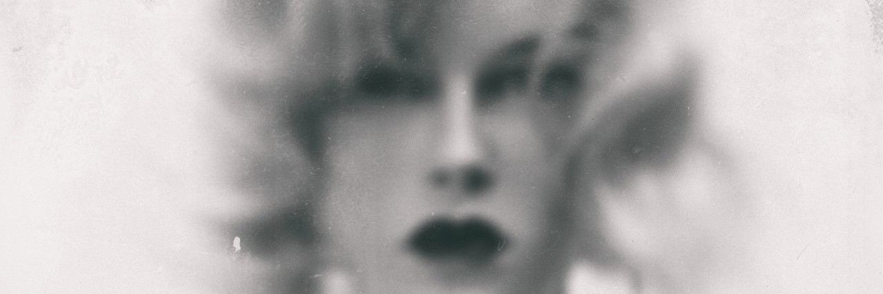 A black and white vintage image of a woman, slightly blurred.