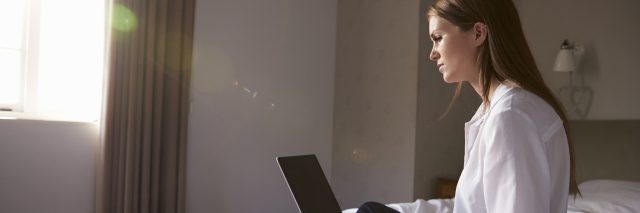 woman sitting on bed with laptop computer