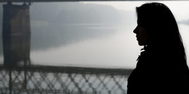 Silhouette girl and bridge over river in autumn