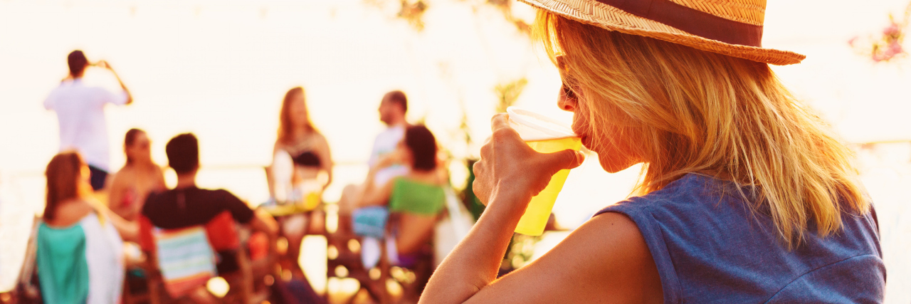 young woman alone at beach party drinking beer