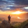 Man standing on a ledge of a mountain, enjoying the sunset over a river valley in Thorsmork, Iceland.