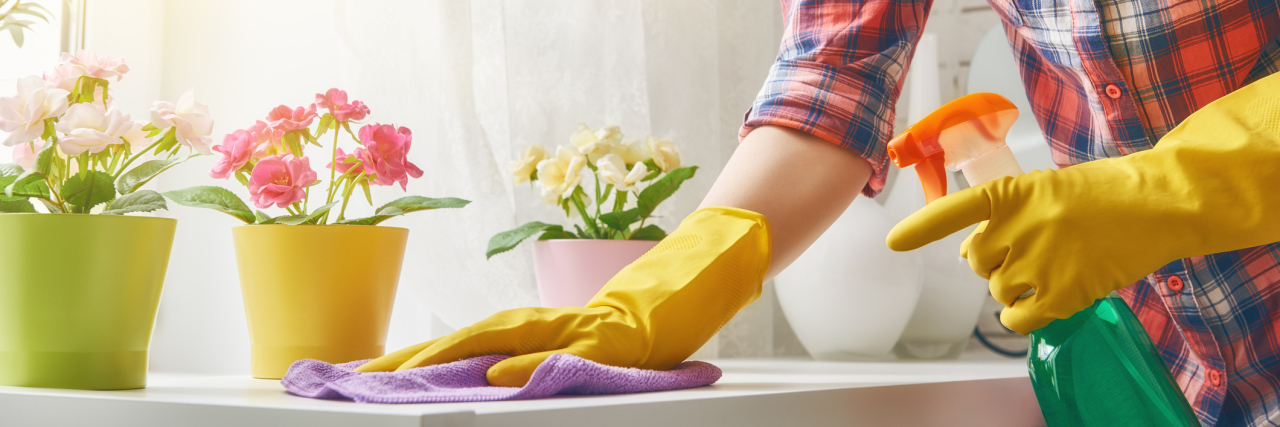 woman cleaning surface wearing yellow rubber gloves