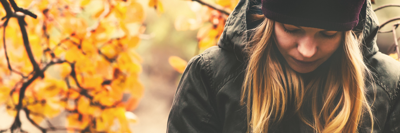 Struggling With the Loneliness of Chronic Illness woman in a jacket and hat standing outside