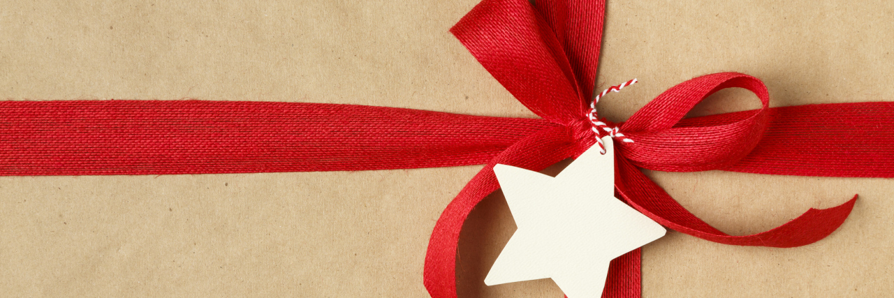 A close-up of a Christmas gift with a red ribbon and bow on top.