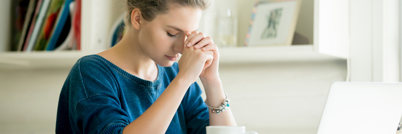 Coping With Outside Stress and Pressure When You Have Lupus woman sitting at a desk looking stressed