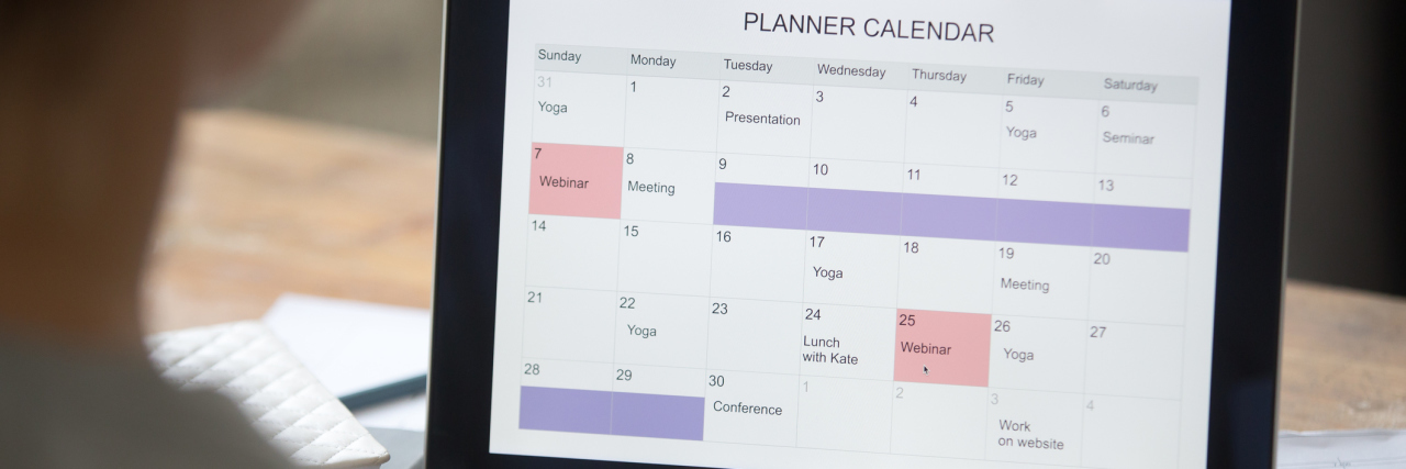 Open laptop on the desk with a planner calendar on the screen.