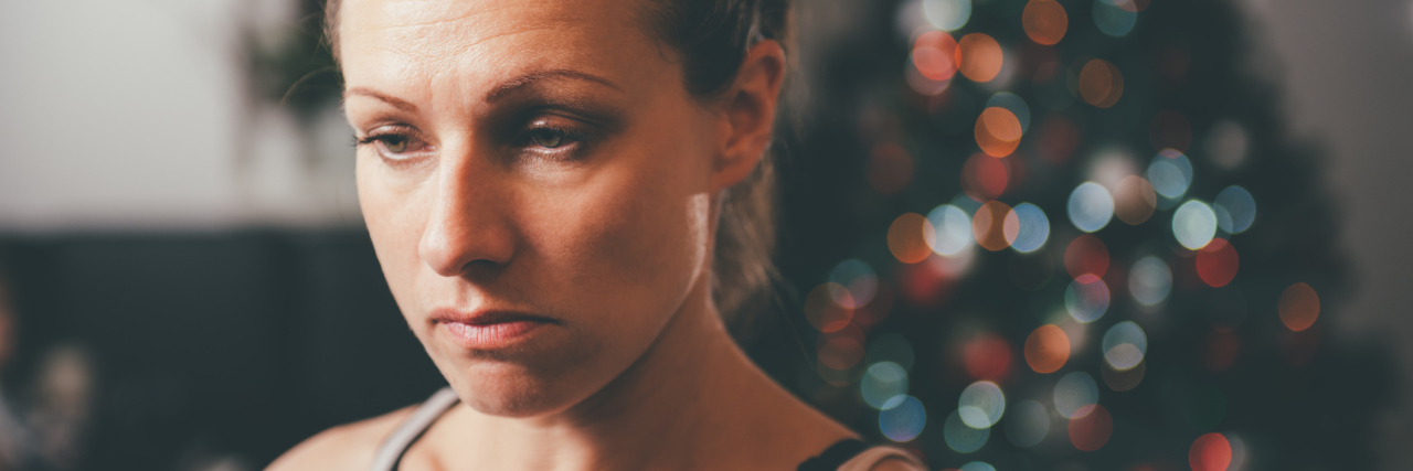 How to Survive a Panic Attack During Christmas woman beside christmas tree sad upset