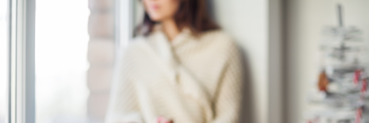 Why I'm Not Setting Health Expectations for the New Year woman sitting on the window ledge next to a christmas tree