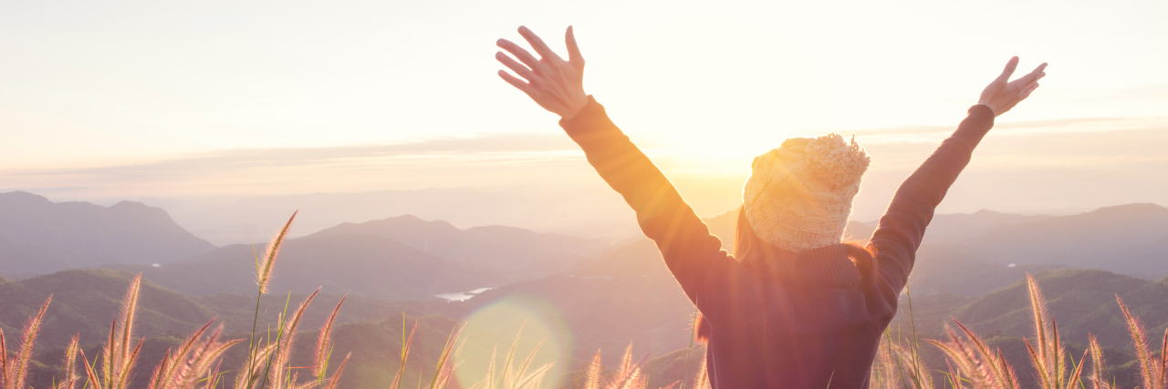 How Mindfulness Saved Me From My Eating Disorder Carefree Happy Woman Enjoying Nature on grass meadow on top of mountain cliff with sunrise. Beauty Girl Outdoor. Freedom concept. Len flare effect. Sunbeams. Enjoyment.