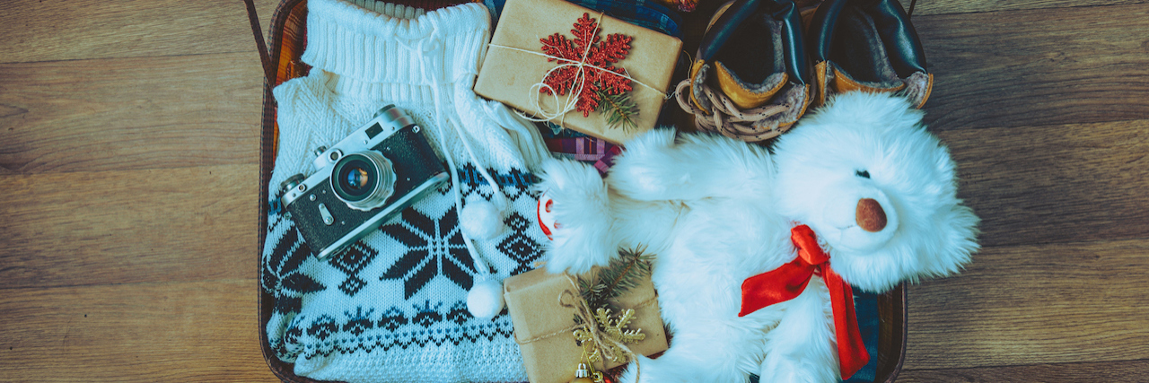 What to Pack If Visiting Family Is Hard on Your Mental Health A suitcase full of clothes and toys for Christmas