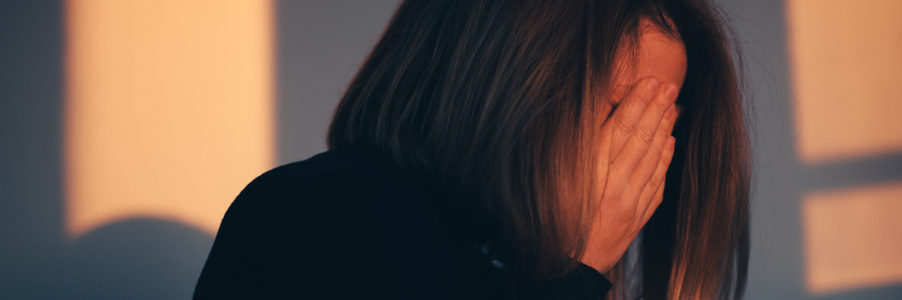 Things People Don't Realize You're Doing When You're in 'Anxiety Pain' A woman sitting alone and depressed in window light