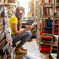 Young woman student with headphones in library.