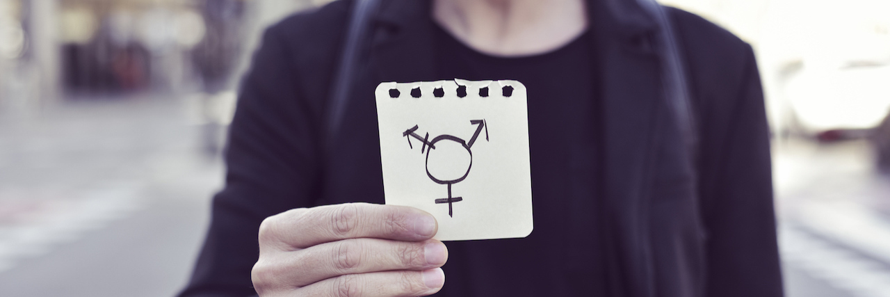 How Politics Affect My Mental Health as a Transgender Man A man holding up the transgender symbol