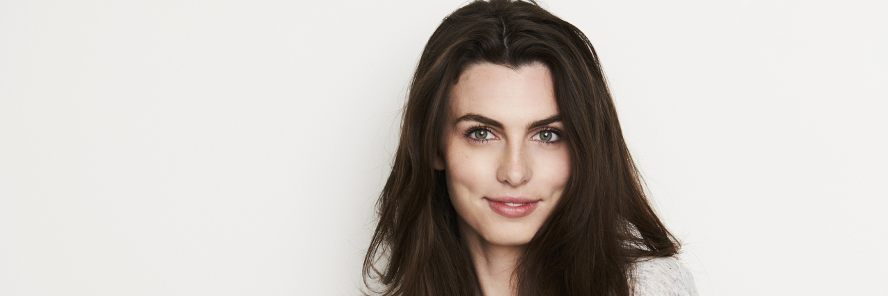 The Struggle of Accepting My Congenital Heart Disease Scars A woman smiling into the camera with confidence.