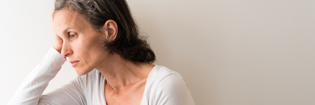 Receiving Adrenal Fatigue Treatment An older woman looking upset, looking outside her window.