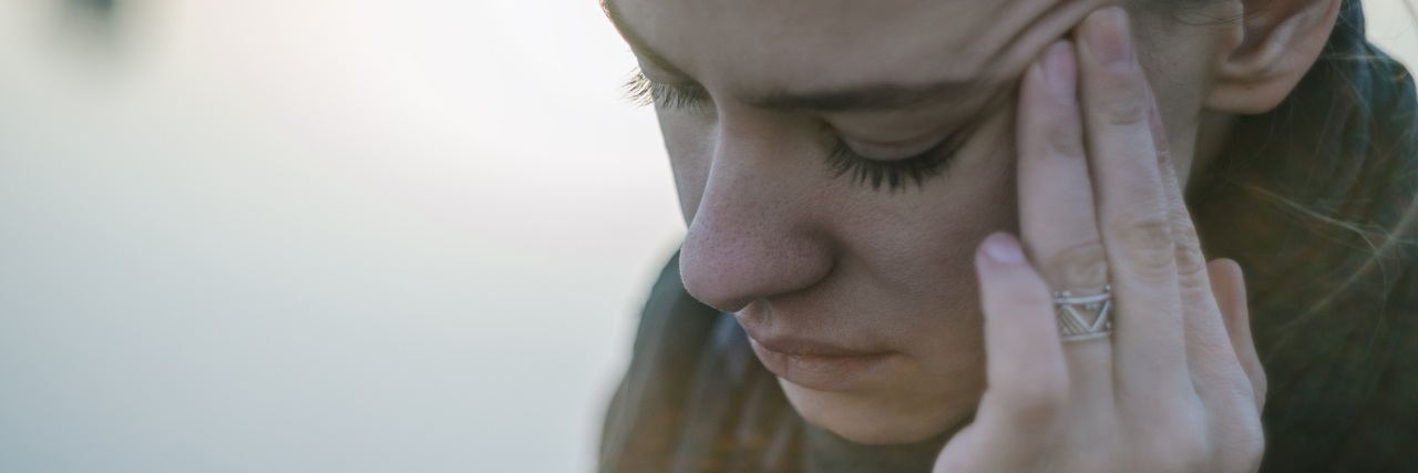 woman touching side of head in pain