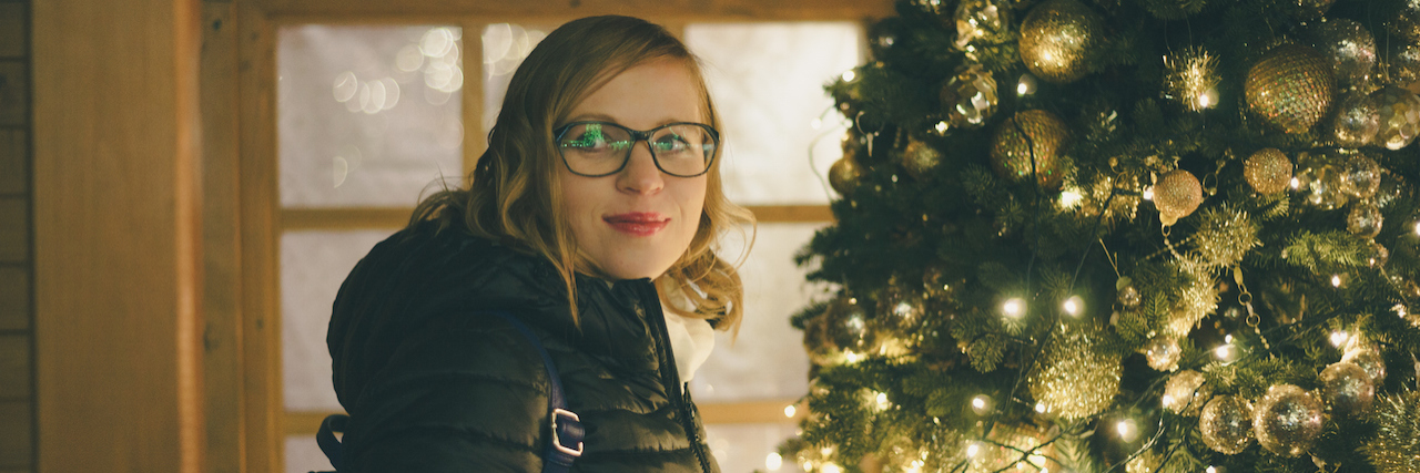 I Have PTSD, and Gift Bags Are a Trigger Woman standing by a Christmas tree