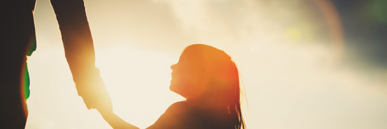 Why I Count the 'Small Mercies' With Morquio Syndrome silhouette of little girl holding parent hand at sunset sky