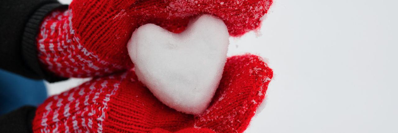 Taking a Rest Day During the Holidays With Chronic Illness woman wearing red gloves and holding a heart of snow