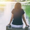 woman sitting alone feeling lonely and thinking missing someone looking out at water lake