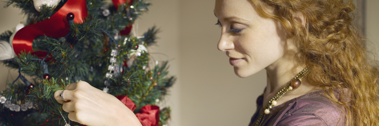 How to Limit Stress During the Holidays When You Have Chronic Illness woman hanging ornament on tree