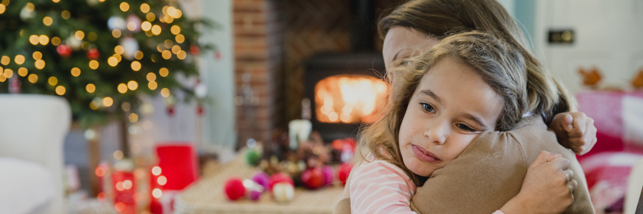 How I'm Celebrating Christmas Through Grief and Depression Sad little girl is cuddling with her mother at christmas time.