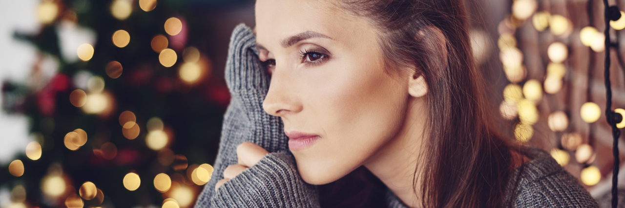 Making New Year's Resolutions With a Chronic Illness woman sitting in front of christmas lights