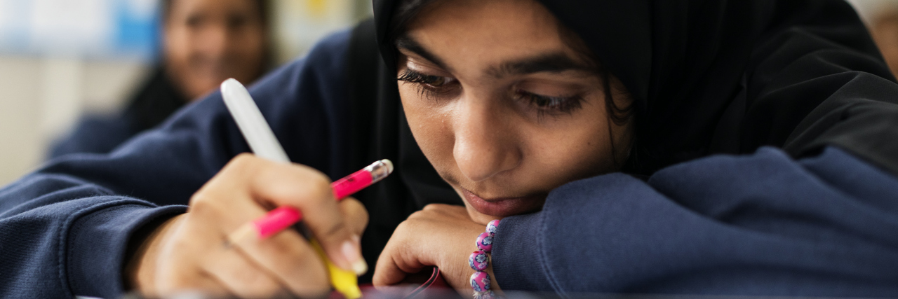 young muslim student leaning on desk looking depressed