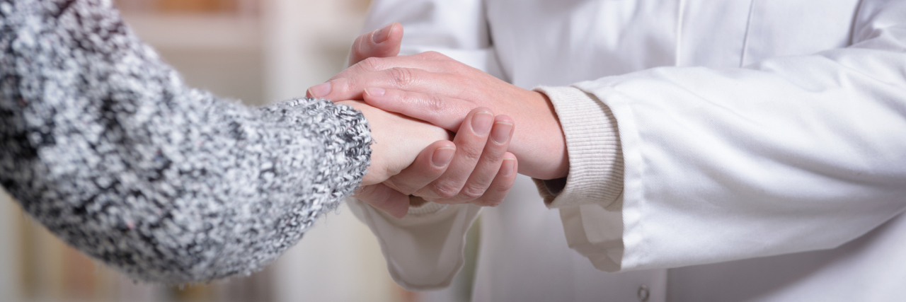 A close-up of a doctor holding a patient's hand.