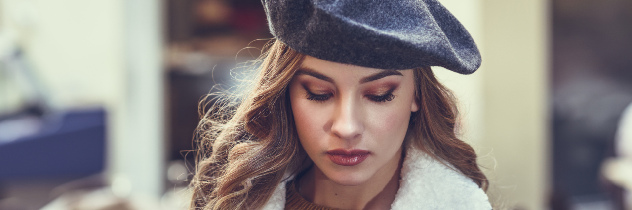 When Your Chronic Illnesses Make Your Weight Fluctuate A woman outside, looking down, with a serious facial expression.