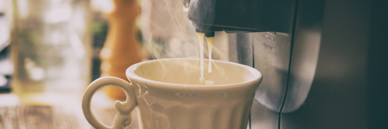 A coffee machine pouring hot liquids into a coffee mug.