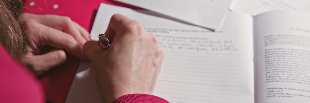 What I Want People to Know About My Test-Taking Anxiety Woman hand writing or signing in a document on a desk at home or office