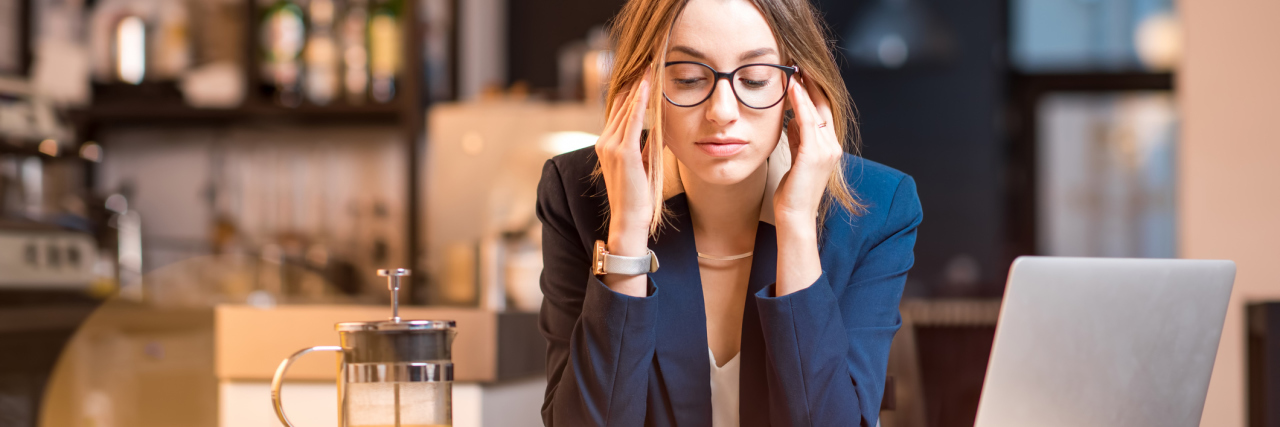 businesswoman in cafe with laptop looking stressed