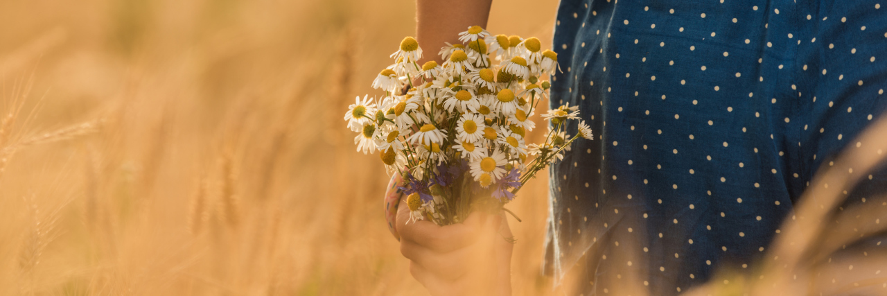 How My Dissociative Identity Disorder Alters Work Together young woman in wheat field with daisy bouquet of flowers