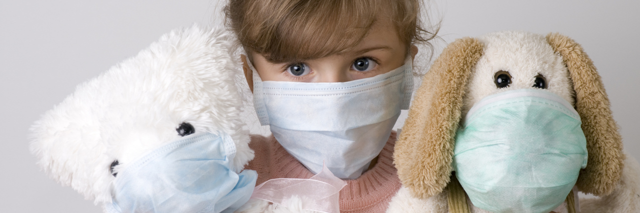 If You're Sick This Christmas Season, Please Stay Home A little girl and her toys wearing medical masks.