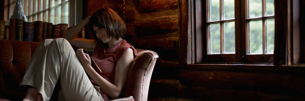 Reading 'Choosing Real' as a Christian With Arnold-Chiari Malformation woman sitting on her couch and reading