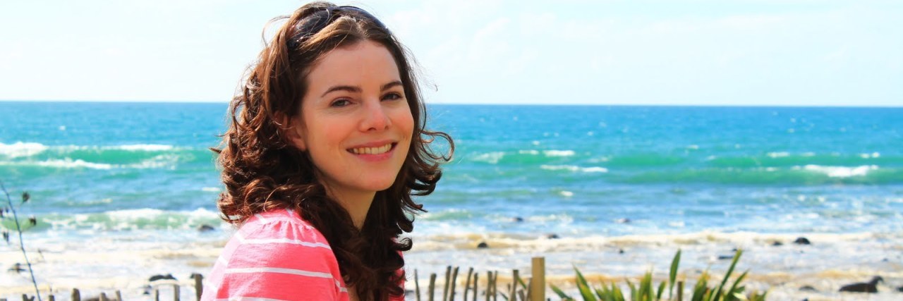 Navigating Pregnancy With Fibromyalgia A photo of the writer with a cody of water behind her.