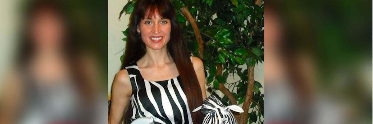 What to Know If You're Newly Diagnosed With a Primary Immunodeficiency woman in a zebra print dress holding a stuffed zebra and medical supplies