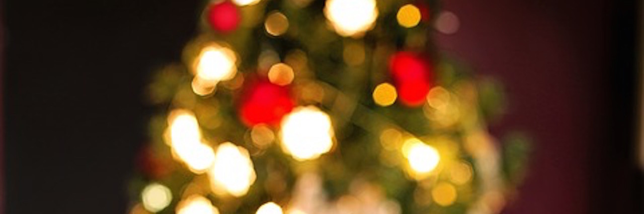 12 Ways You Can Support Your Friend With Lyme Disease This Christmas Christmas cookies and a coffee mug in front of a lit-up Christmas tree.