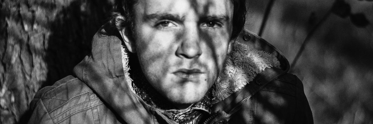 Faith Isn't Always About Religion as Someone With Depression man sitting under a tree in black and white with shadows on his face