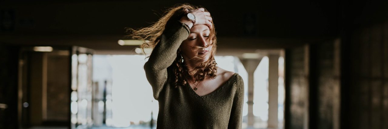 What the Physical Symptoms of Anxiety Mean for Stigma woman in warehouse or tunnel with hand to head